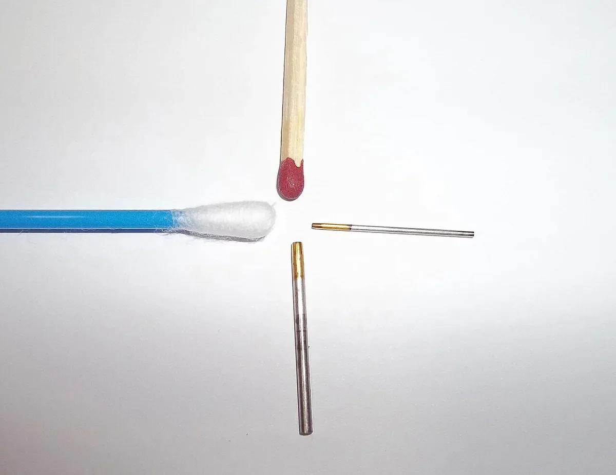 Two FUE extraction needles of different sizes used in hair transplant graft harvesting, beside a match