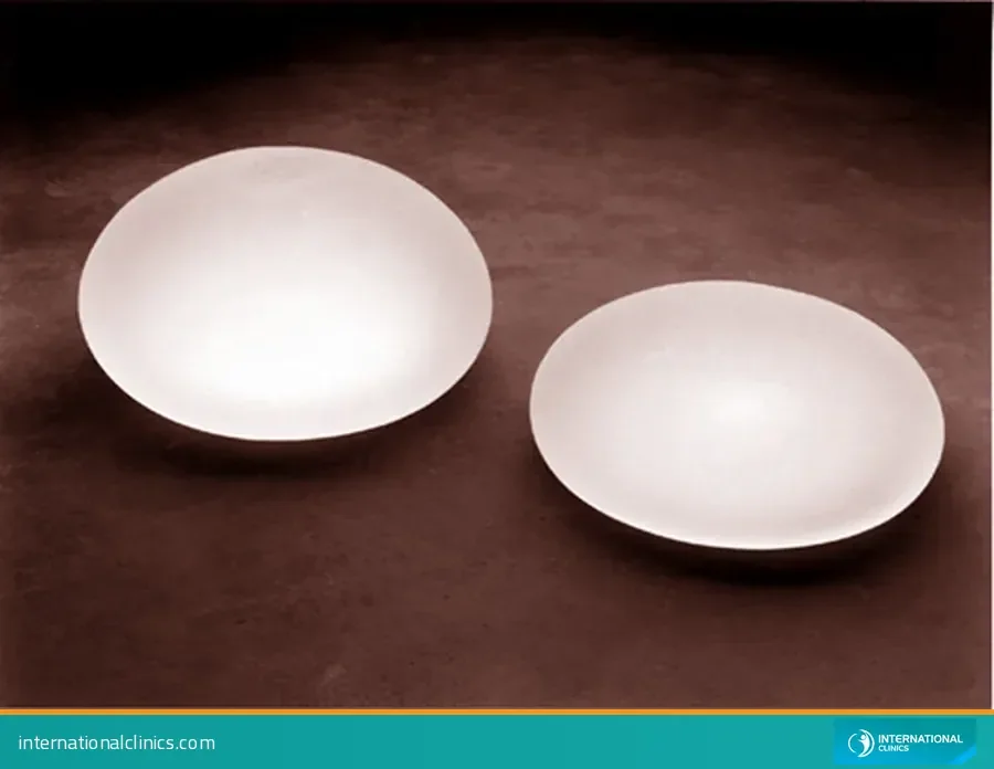 Two saline-filled breast implants on a brown surface, one of the implant types that affects boob job prices