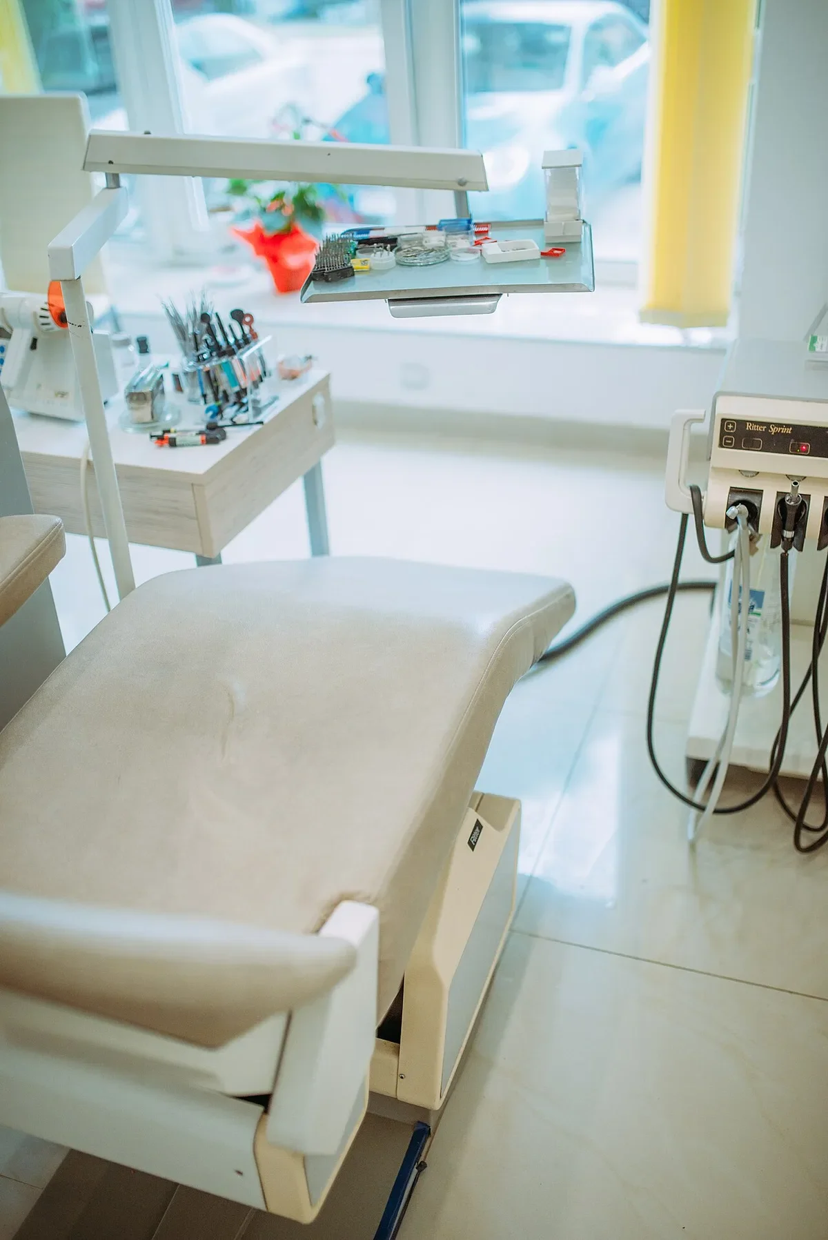 Salle de soins lumineuse d’une clinique dentaire moderne avec fauteuil, unit et instruments